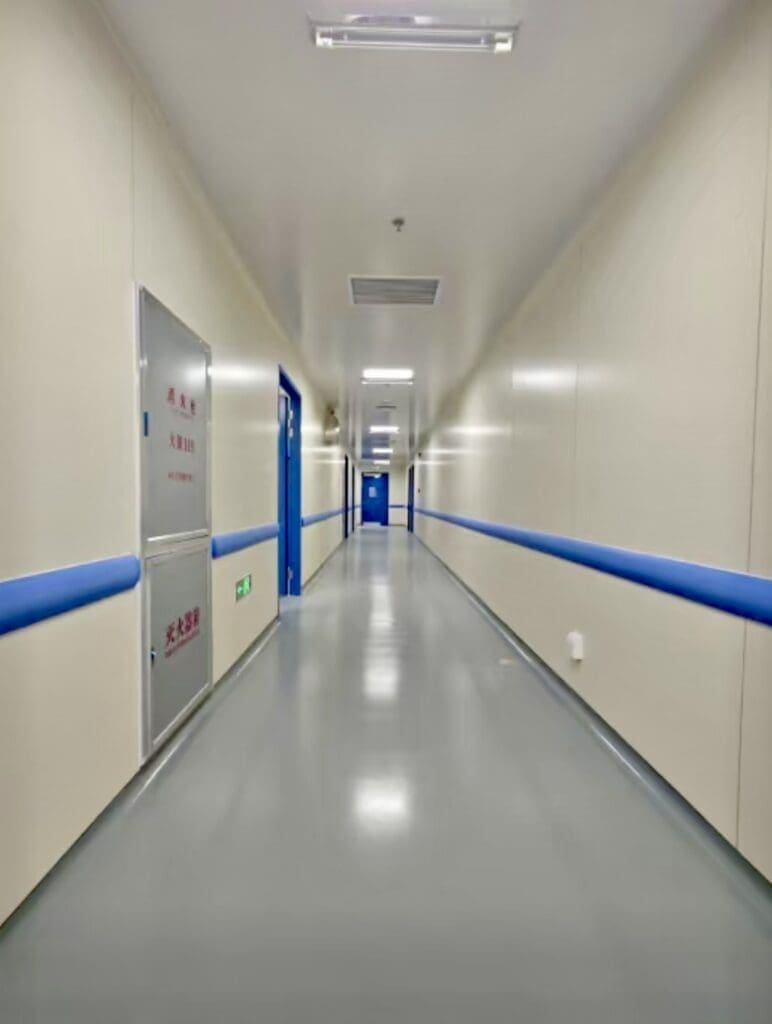 Hospital hallway with blue railings and doors.