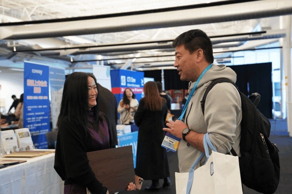 Two people talking at a convention booth.